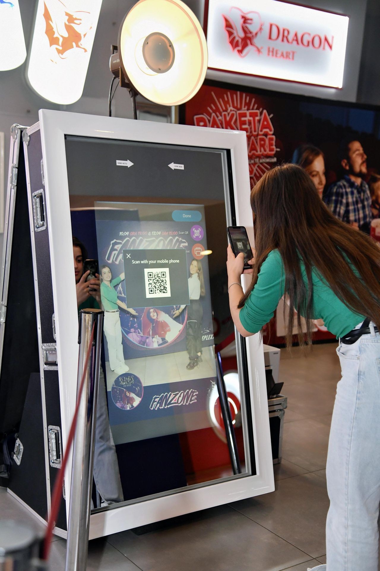 Person scanning a QR code on a large digital display with a smartphone at an entertainment venue.